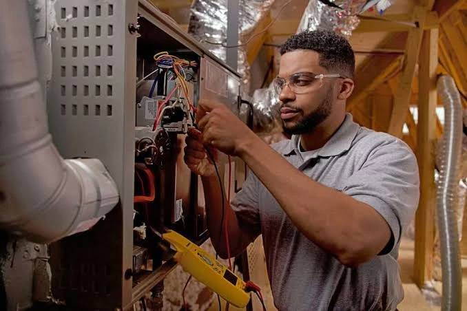 Technician inspecting furnace wiring and controls in an attic